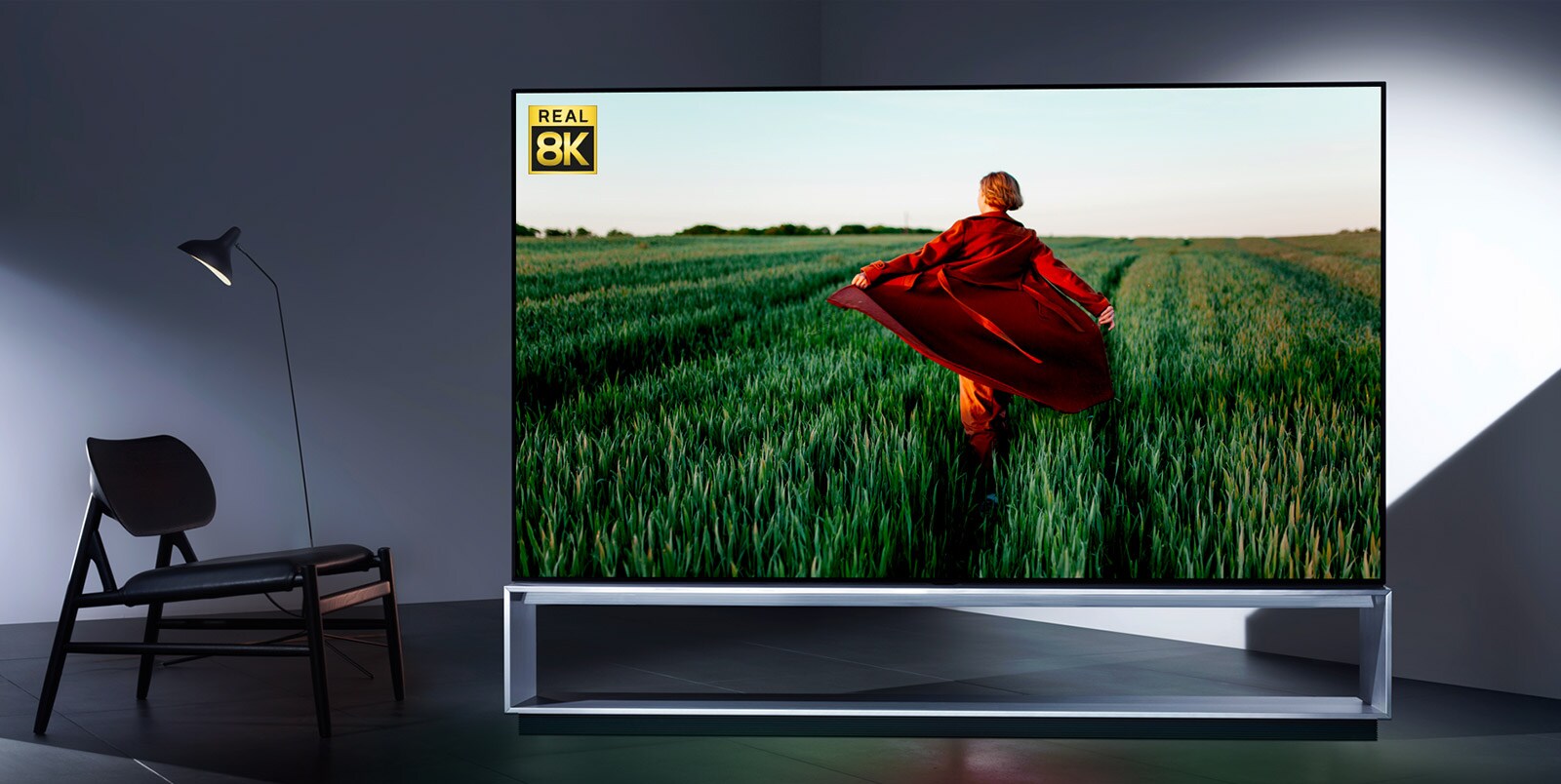 Un téléviseur LG OLED 8K présentant le réalisme de la 8K à partir d’une image d’une femme en trench rouge courant dans une rizière verte