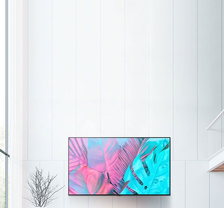 Un grand écran plat fixé sur un mur blanc. L’écran affiche de grandes feuilles dans des couleurs lumineuses.