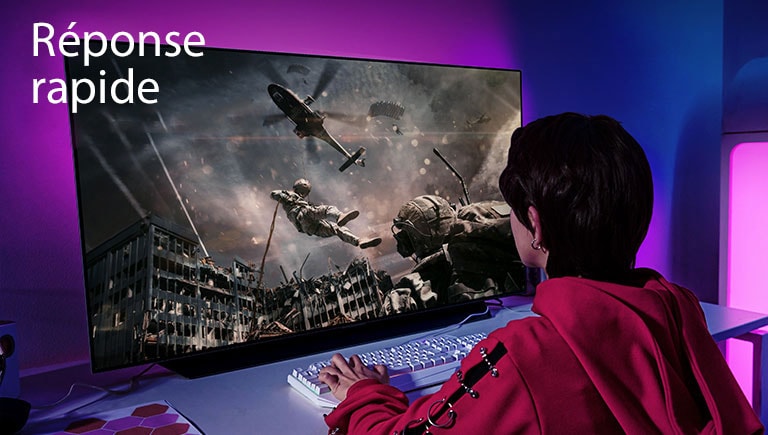 Une fille jouant à un jeu d’ordinateur avec un téléviseur grand écran affichant un soldat descendant d’un hélicoptère.