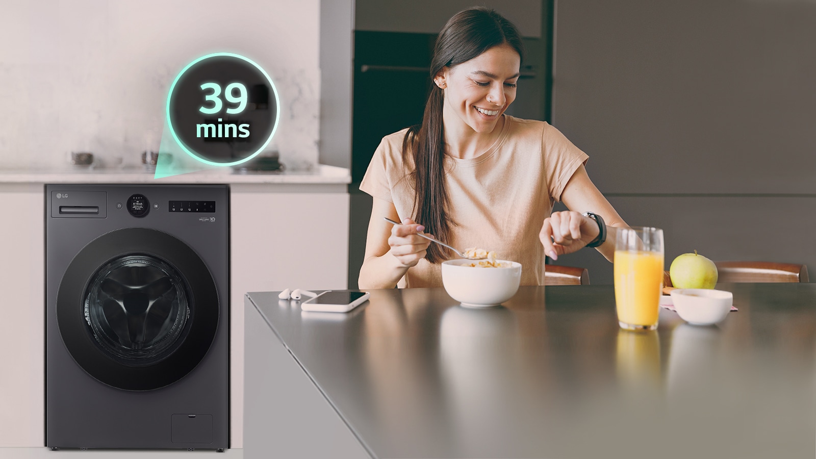 The woman is sitting at the table looking at her watch, and there is a washing machine behind her
