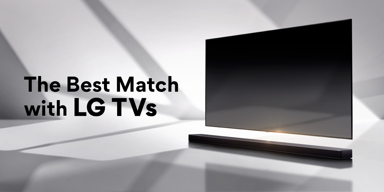 A soundbar and a TV are placed on a white floor and there is a shadow coming from outside right behind.