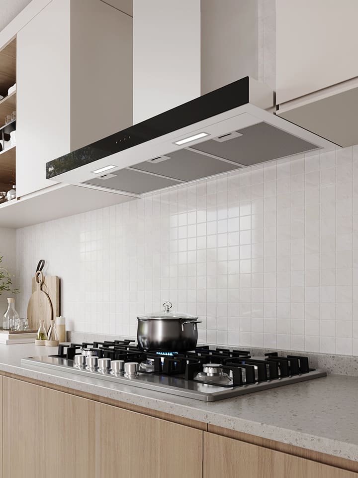 Modern kitchen interior featuring a built-in hood above a gas cooktop with a pot, against a white tile wall.