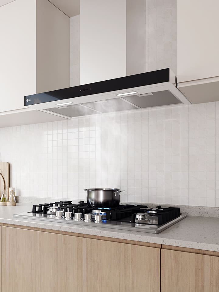 Modern kitchen interior featuring a built-in hood above a gas cooktop with a pot, against a white tile wall.