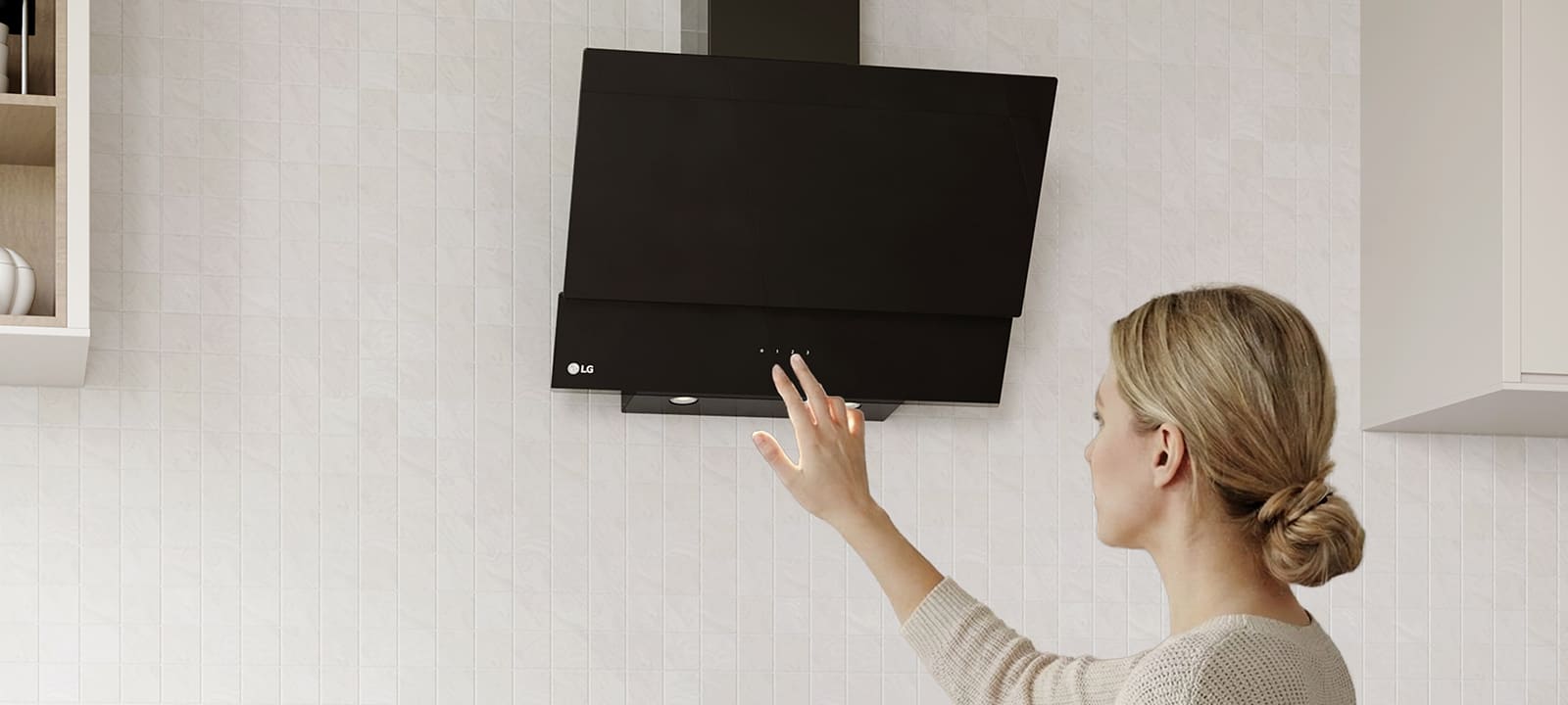 A woman adjusting the touch controls of a black glass hood above a cooktop in a modern kitchen with a white tile wall.