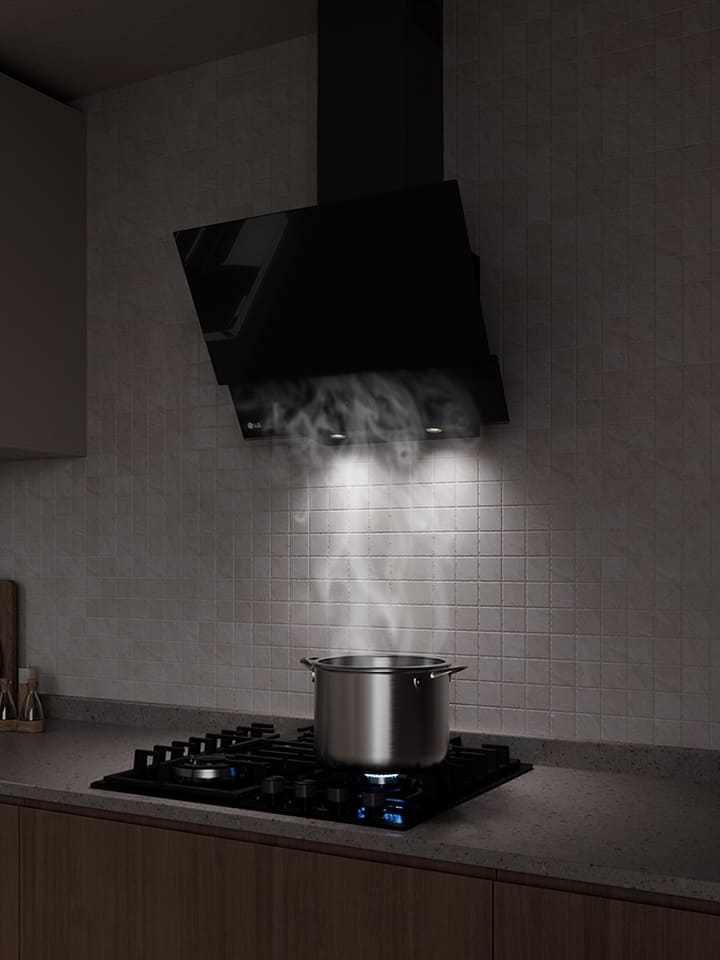 A black glass hood above a gas cooktop draws in steam rising from a pot while cooking in a modern kitchen.