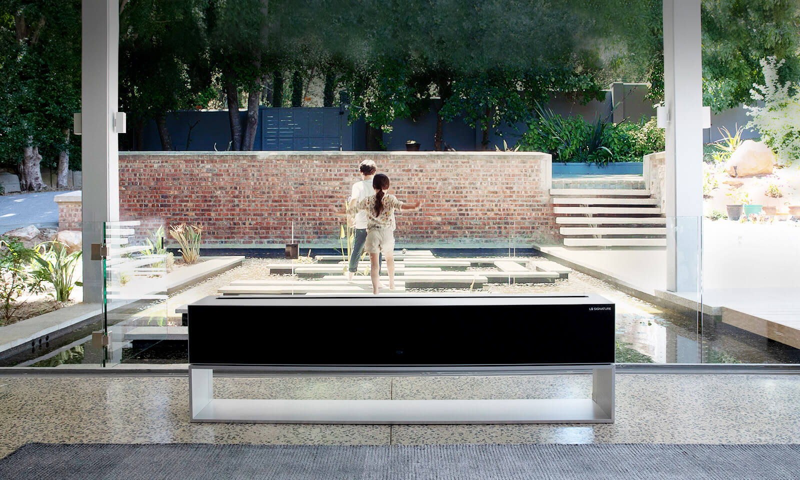 The screen of Rollable TV disappears in front of the pond in the luxury house, revealing the children playing behind