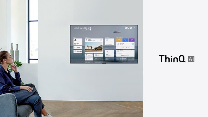 Woman sitting on a chair in the living room with the Home Dashboard on the TV screen