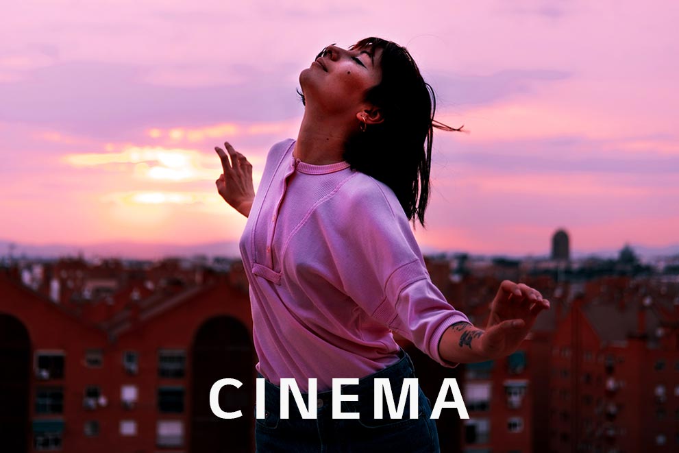 A bust shot of girl happily dancing on a roof at the magic hour