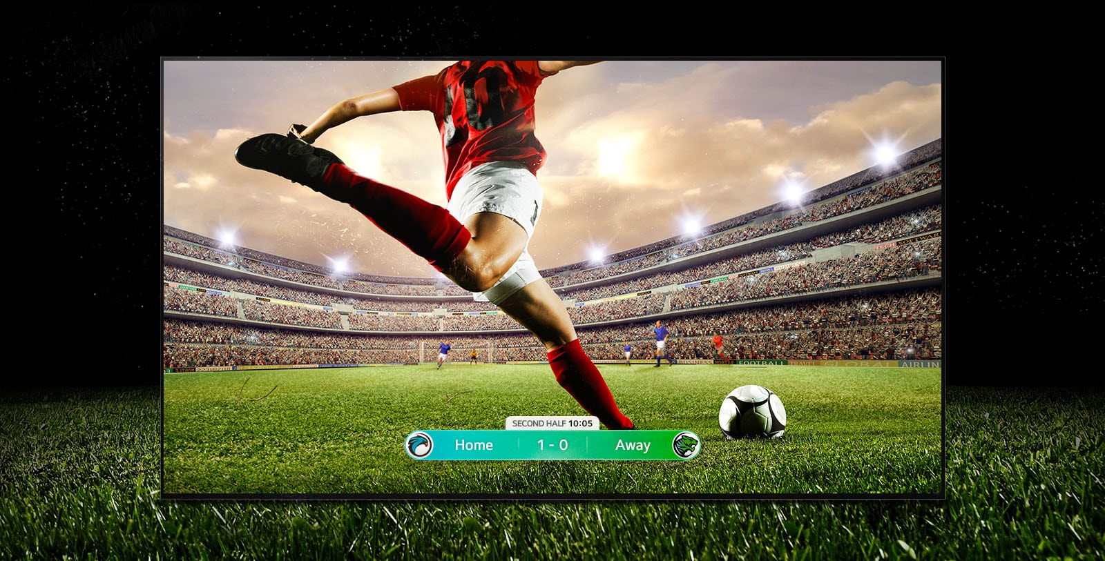 An image of the display showing a soccer game with a player in a red strip about to kick the ball across the stadium. The game score is visible at the bottom of the screen. The green grass from the pitch stretches beyond the screen to the black backdrop.