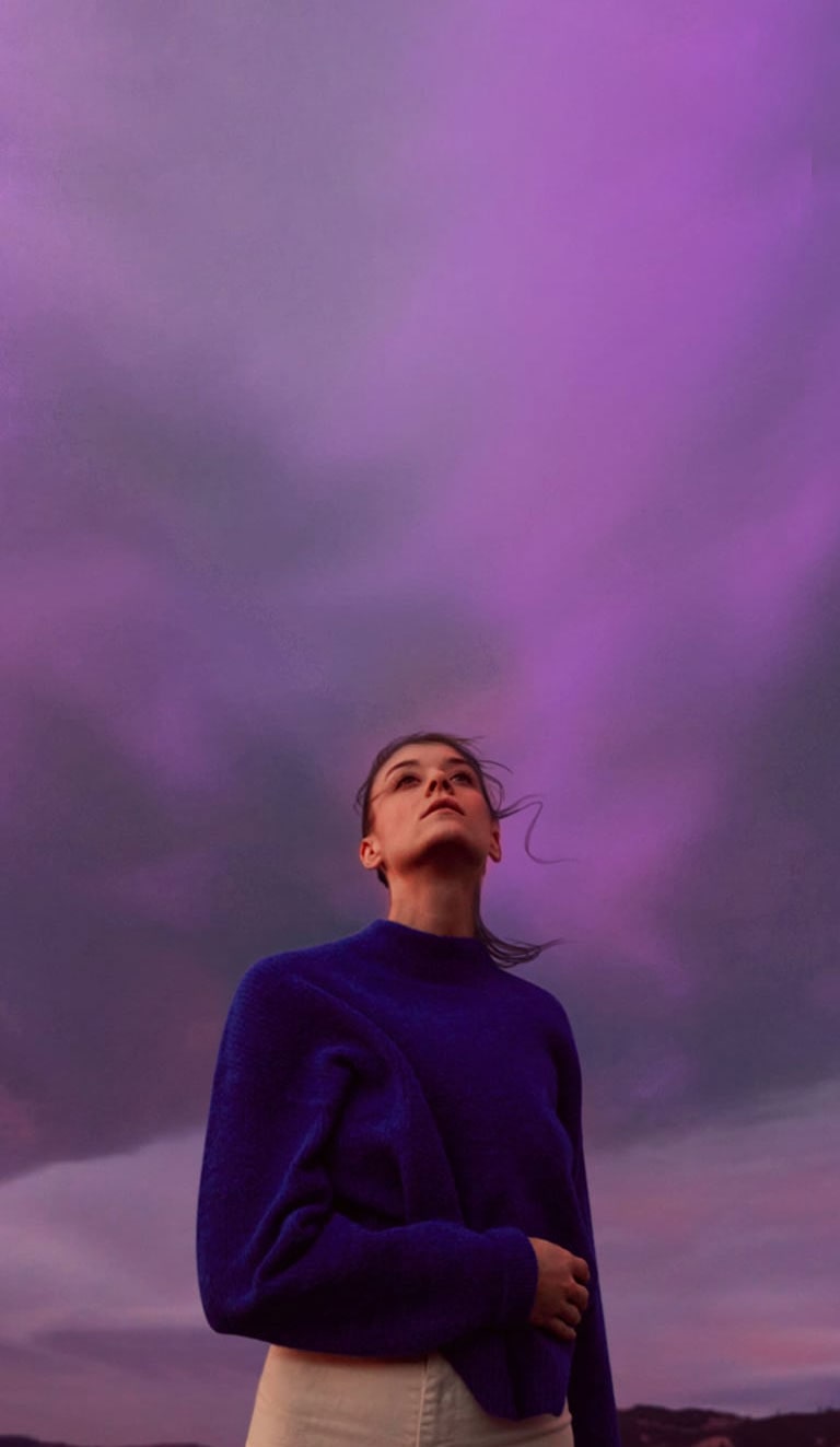 A woman is looking at a purple sky. Her hair is slightly shaking.