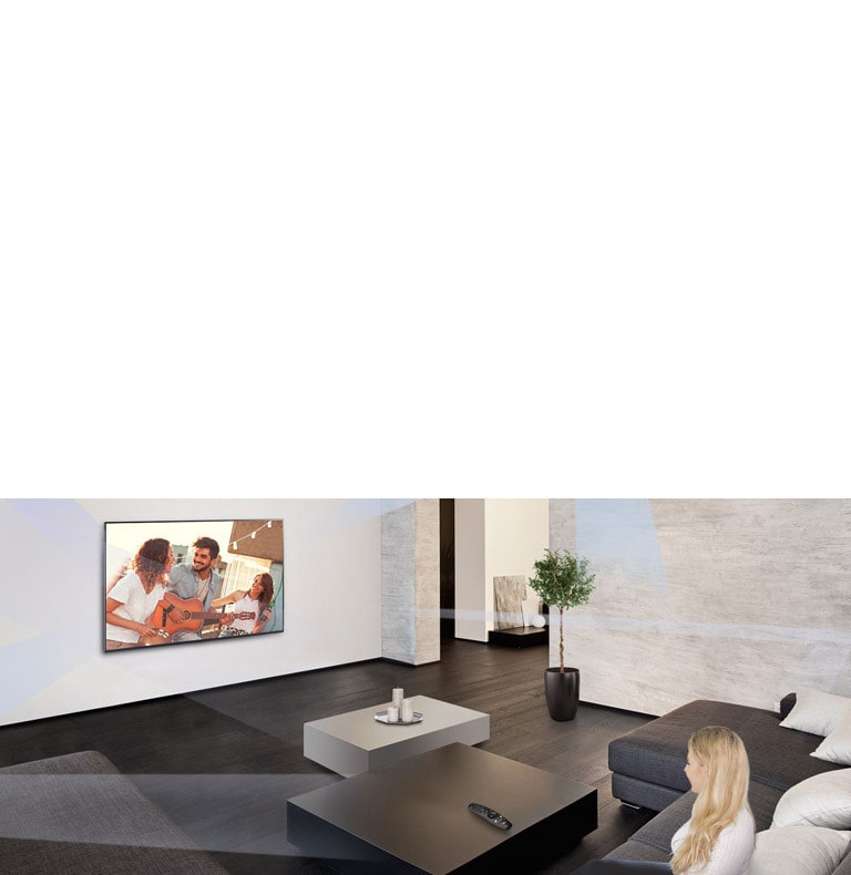 Women in the large and minimalistic living room watching people playing on TV.