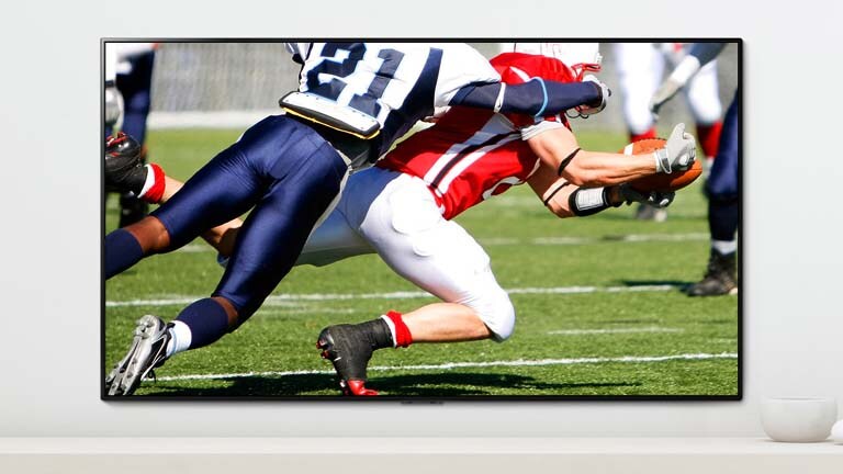 A scene of a sports game showing two men who are playing dynamically playing American football on a TV screen