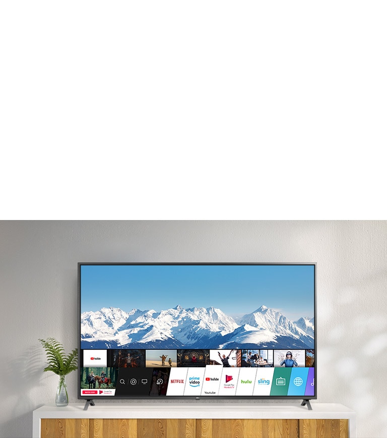 TV standing on a white stand against a white wall. TV screen shows home screen with webOS.