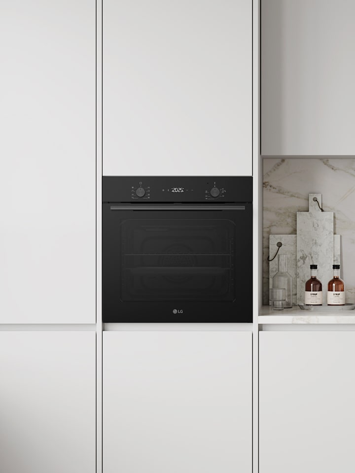 Modern white kitchen with built-in black radiant cooktop, oven, hood, and sink.