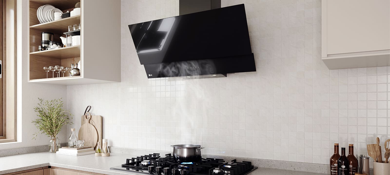 Modern kitchen interior featuring an angled glass hood above a gas cooktop with a pot, against a white tile wall.