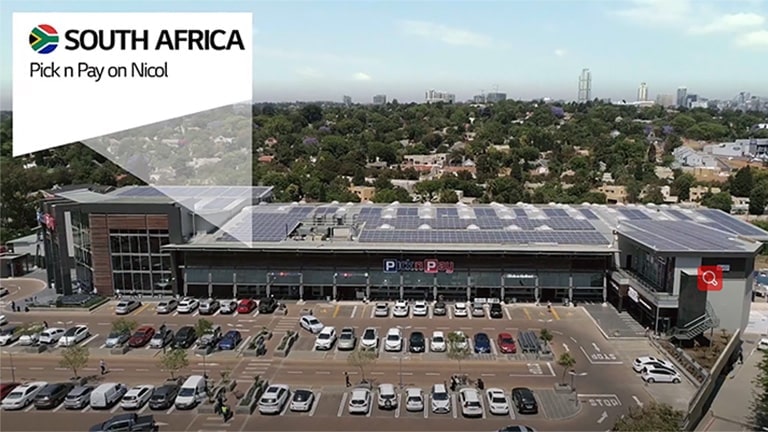 From a bird's eye view, a large structure presides over a bustling parking lot, densely packed with a variety of cars.