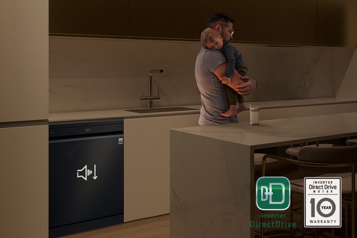 Man holding a sleeping child while a quiet dishwasher runs in the background