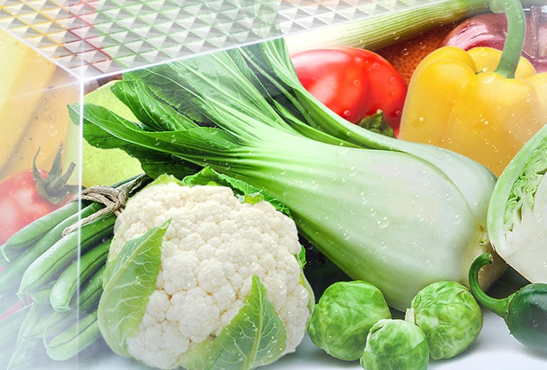 Fresh and vibrant vegetables are shown inside the vegetable crisper drawer.