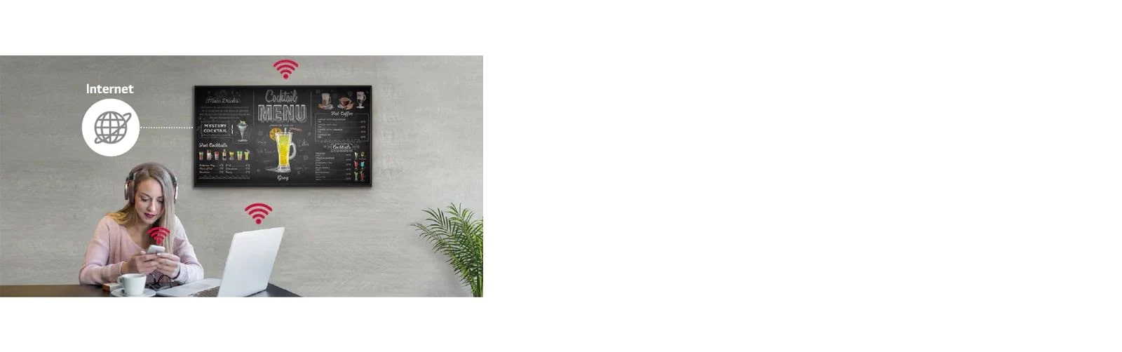 Con la serie UR3J montada en la pared, una mujer usa una PC y un teléfono móvil. Esta imagen muestra que la pantalla Signage puede conectarse de manera inalámbrica a la PC y al teléfono móvil que sostiene.