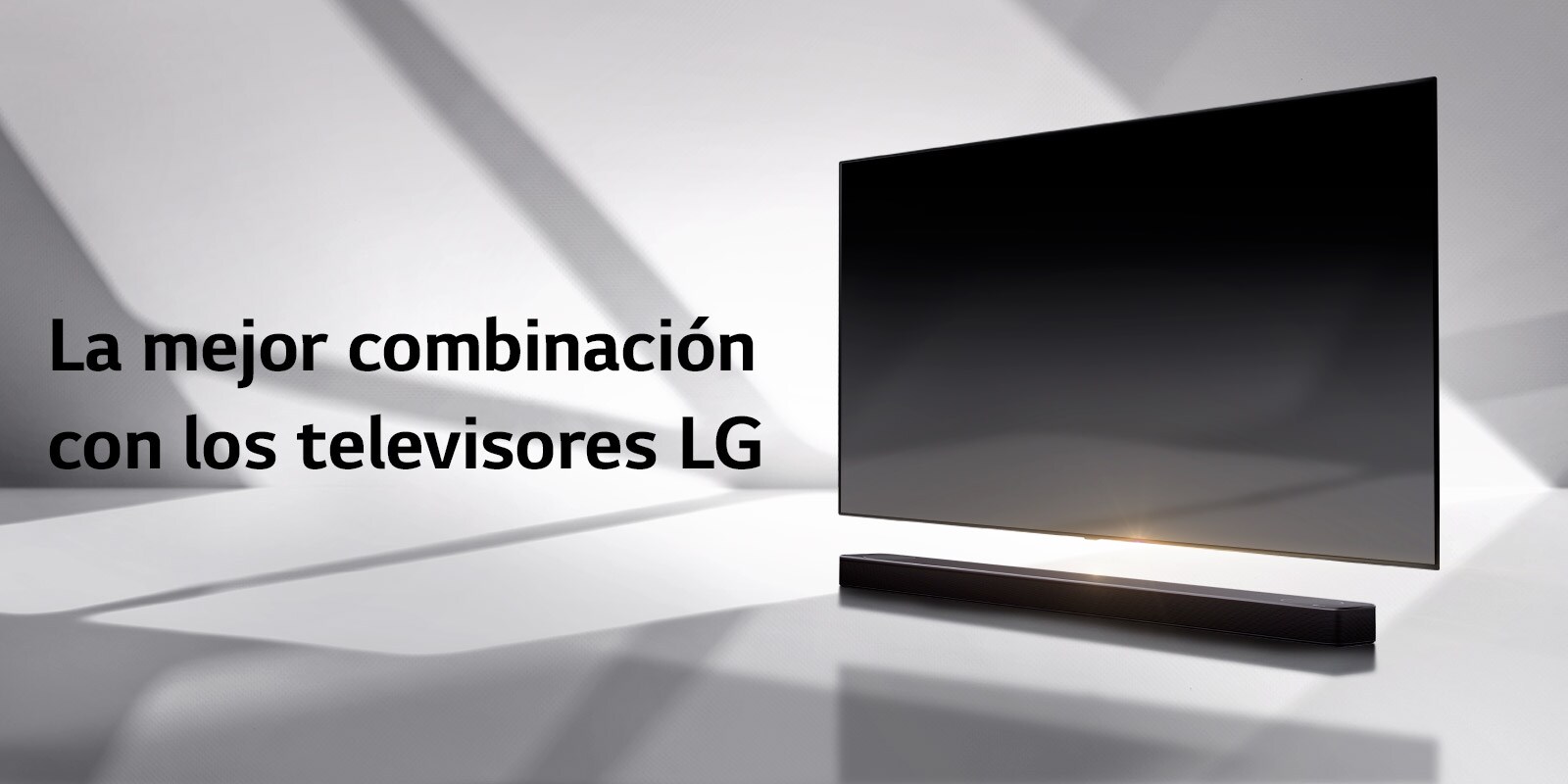 Una barra de sonido y un televisor están situados en un suelo blanco y por detrás aparece una sombra que viene del exterior.