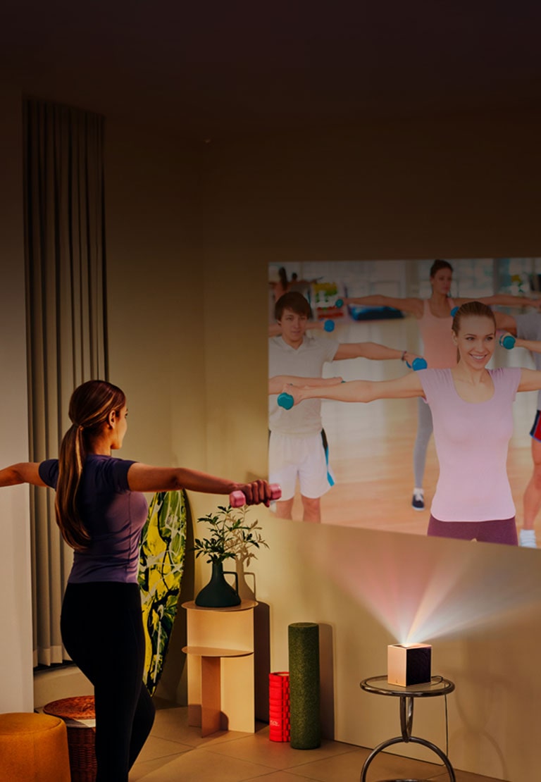 Mujer haciendo yoga con proyección LG CineBeam de fondo.
