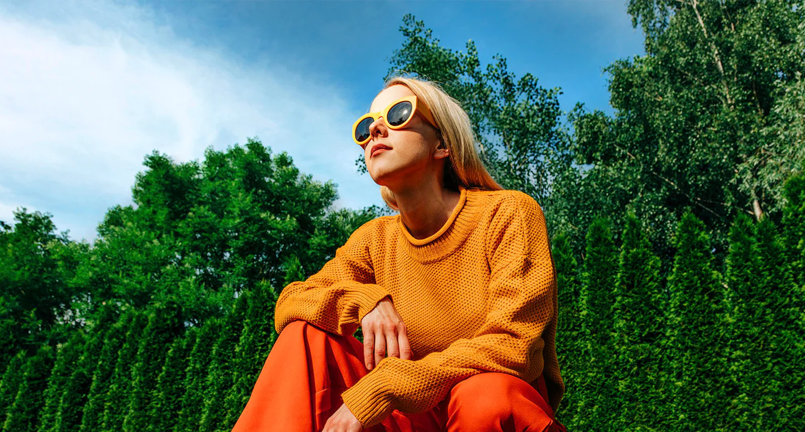 Una mujer agachada afuera en un día soleado frente a los árboles y un cielo azul, en una imagen oscur y pixeleada. El efecto de mapeo tonal y potenciador de la expresión recorre a la mujer, haciendo que la zona sea más luminosa. Luego se escanea el fondo, haciendolo más brillante.