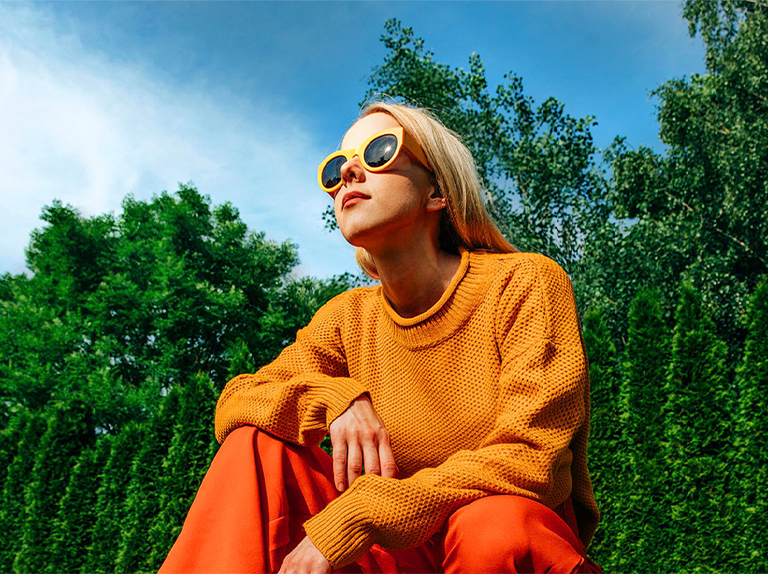 Una mujer agachada afuera en un día soleado frente a los árboles y un cielo azul, en una imagen oscur y pixeleada. El efecto de mapeo tonal y potenciador de la expresión recorre a la mujer, haciendo que la zona sea más luminosa. Luego se escanea el fondo, haciendolo más brillante.
