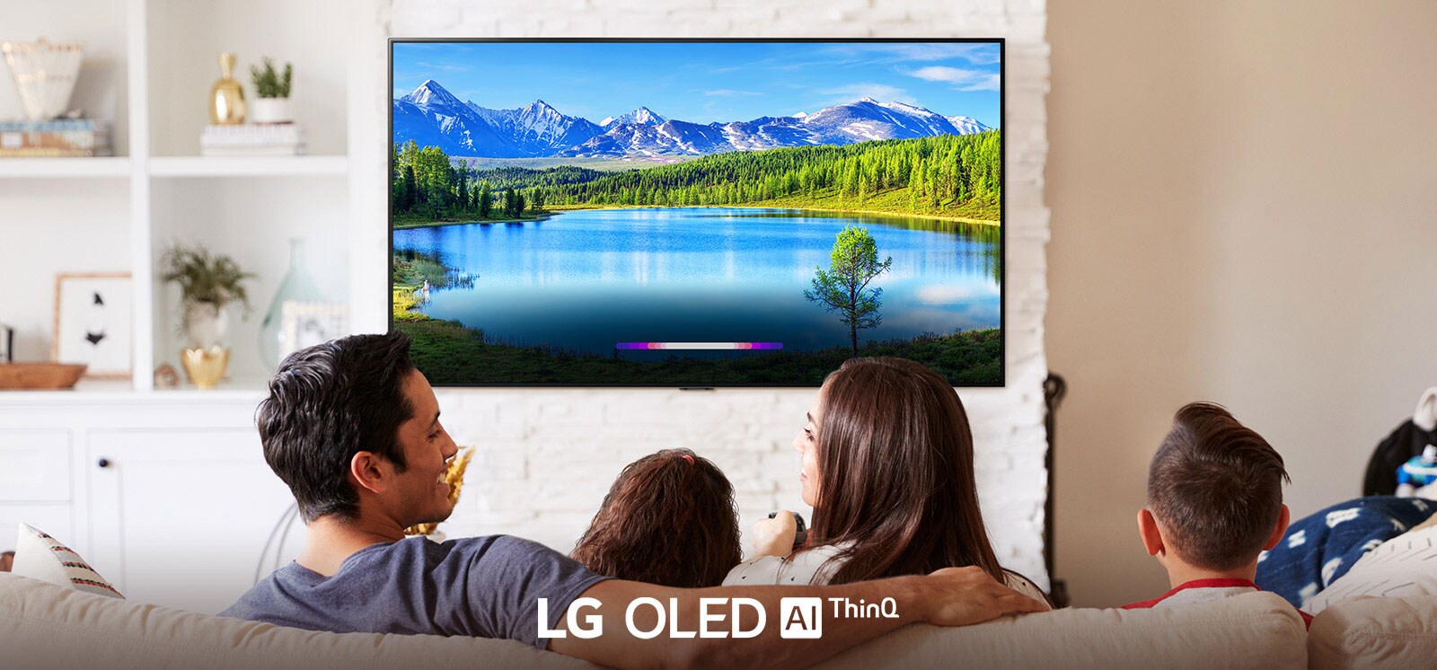 Familia en una sala de estar luminosa mirando el paisaje en la televisión montada en la pared