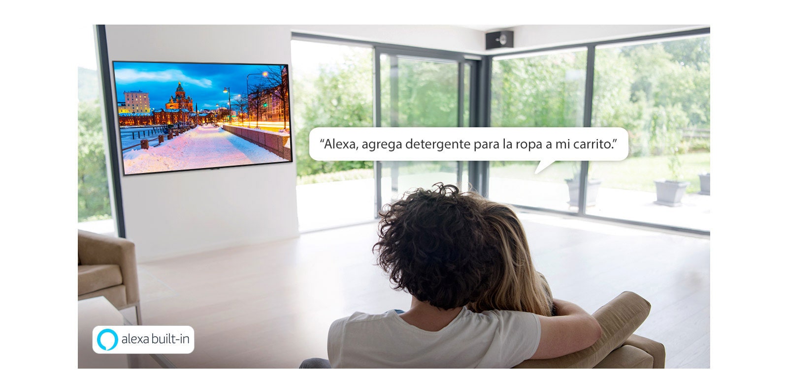 Pareja sentada en un sofá pidiéndole a Amazon Alexa que agregue detergente para la ropa al carrito de compras