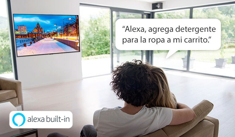 Pareja sentada en un sofá pidiéndole a Amazon Alexa que agregue detergente para la ropa al carrito de compras