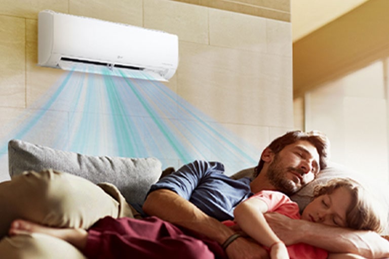 Un padre y una hija duermen en un sofá debajo de un aire acondicionado que sopla aire sobre ellos.