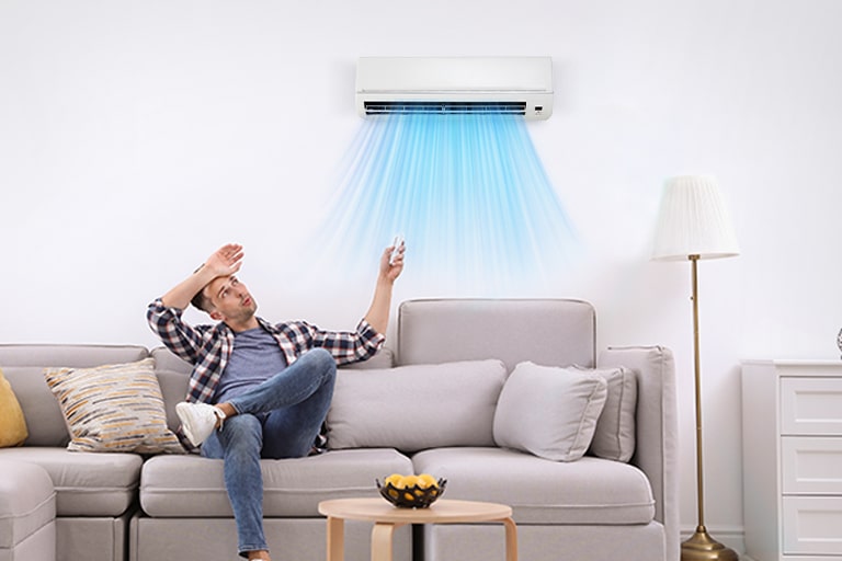 Aire acondicionado en la pared soplando aire frío, pero el hombre en el sofá parece tener calor