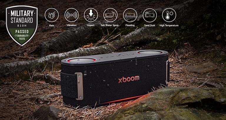 El xboom Bounce está sobre hojas mojadas, entre una raíz y una piedra. En la esquina superior izquierda, el logo militar.