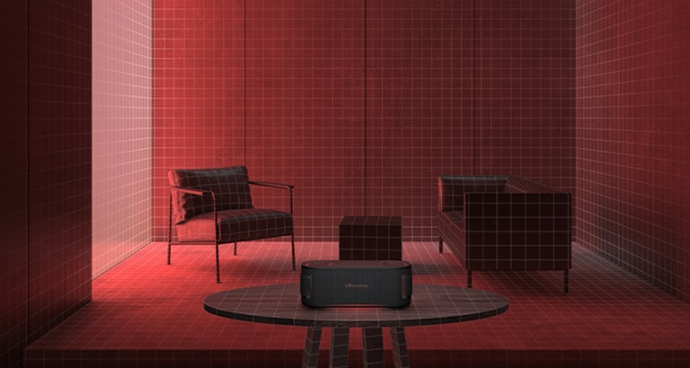 En una habitación iluminada con una luz rosa, se ubican un sofá blanco y una mesa detrás. Al frente, xboom Grab está sobre una mesa rectangular blanca.