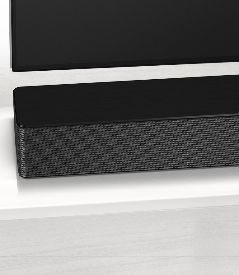 Primer plano de la esquina izquierda de la barra de sonido LG. También puede verse la parte inferior izquierda de la TV.