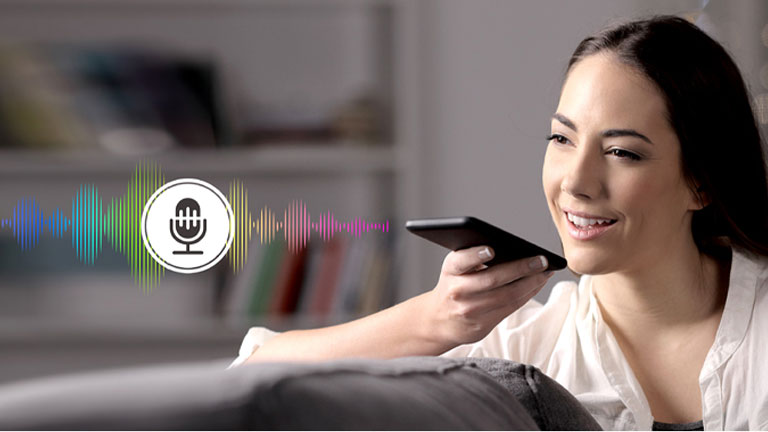 Una mujer controla la TV hablándole a un control remoto con reconocimiento de voz.