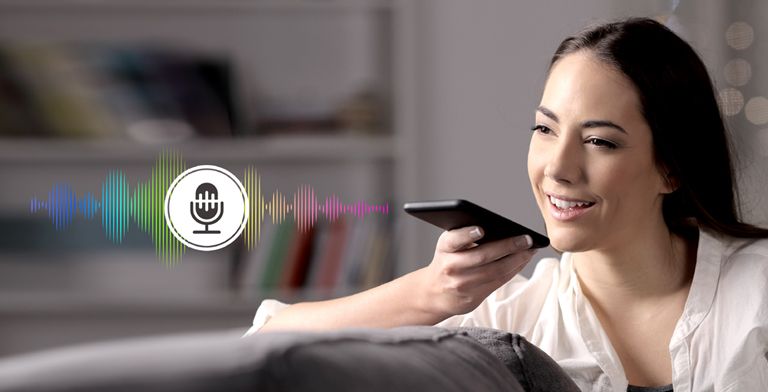 Una mujer controla la TV hablándole a un control remoto con reconocimiento de voz.