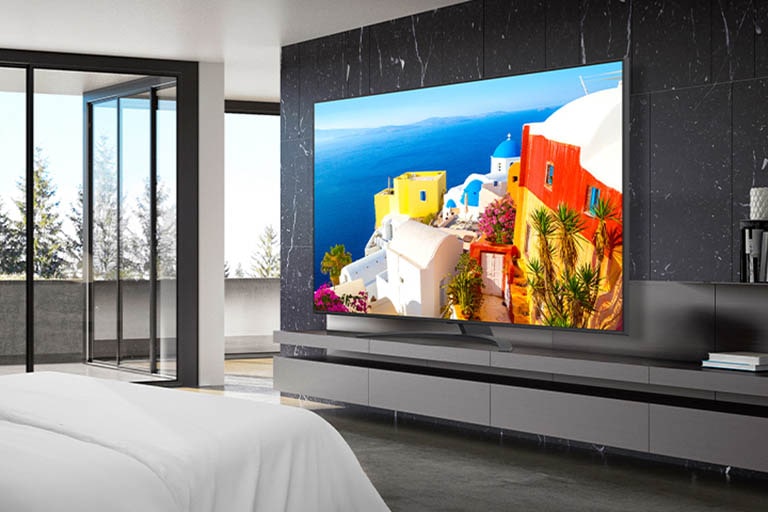 Hay un televisor instalado en un soporte cerca de la pared de la habitación del hotel, y la pantalla es brillante y nítida.
