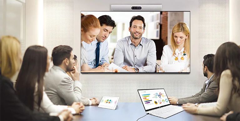Se está realizando una videoconferencia, mientras las personas se proyectan en los carteles instalados en la pared.