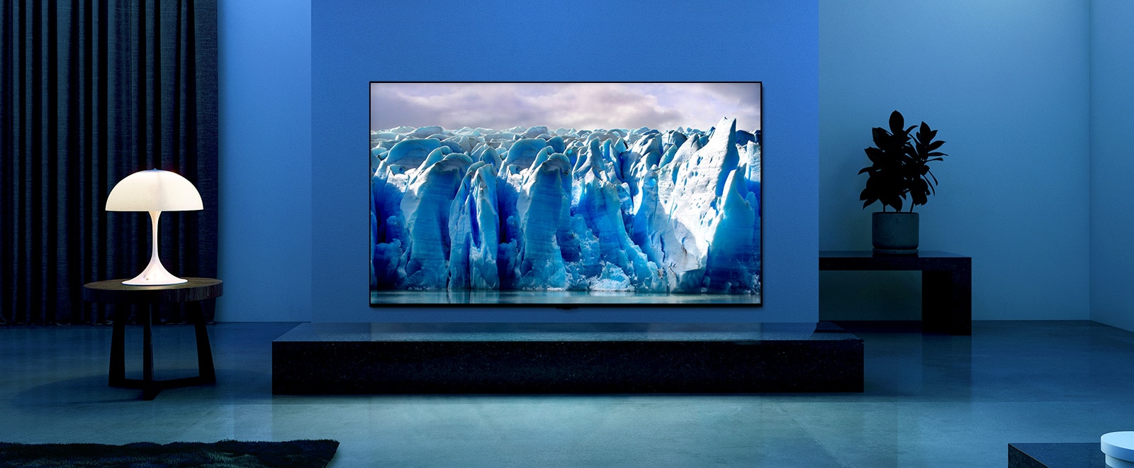 El video muestra un primer plano de la imagen del iceberg y hay un efecto visual del circuito azul sobre la imagen del iceberg. La escena cambia para mostrar un televisor colgado en la sala de estar con iluminación y fondo azules. Hay un gran iceberg en la pantalla del televisor.