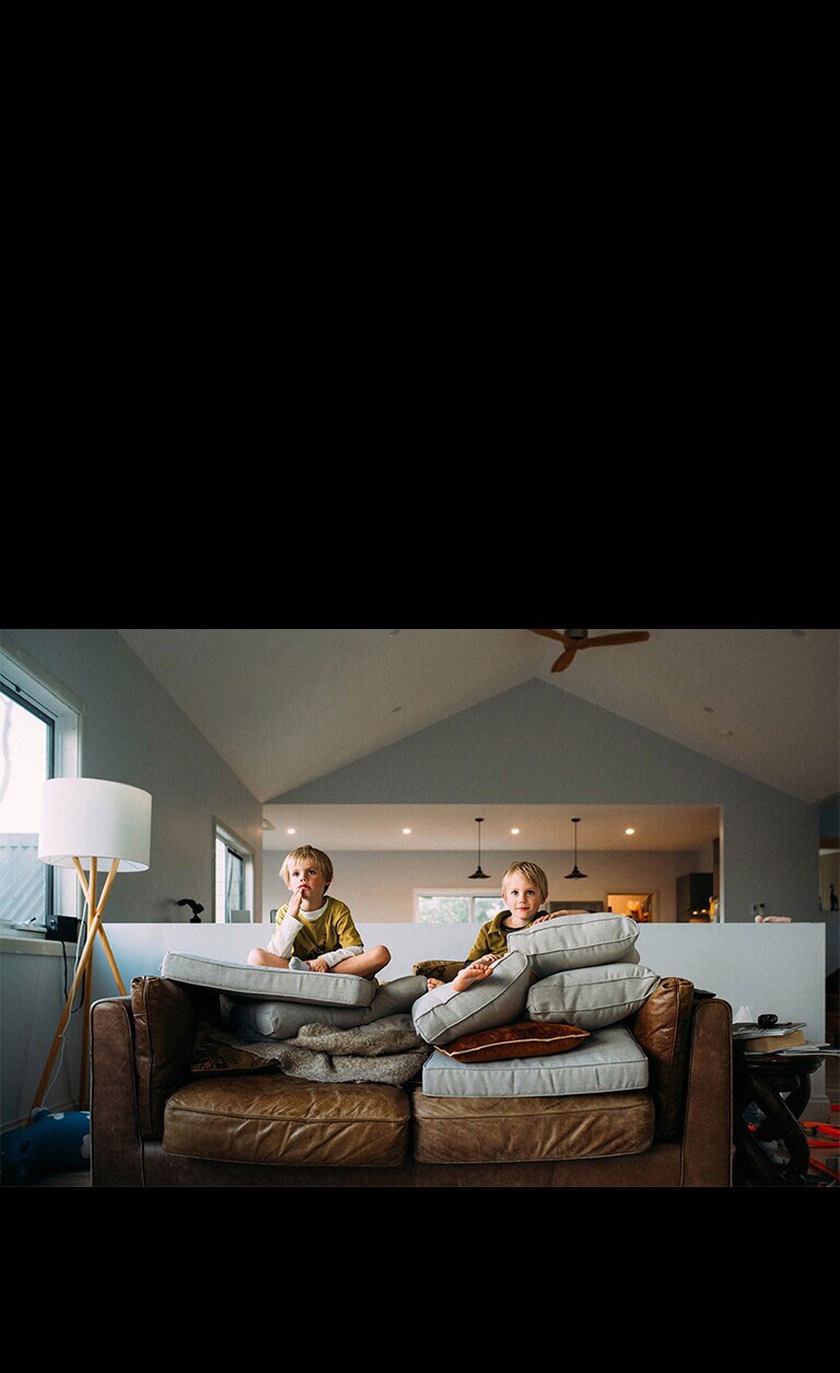 Dos gemelos miran algo sentados en un sofá.