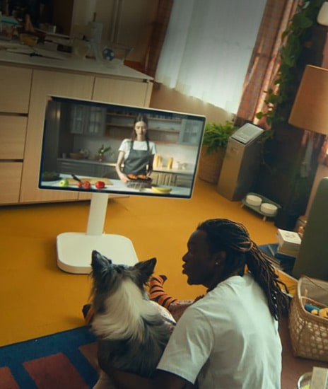 Un hombre está viendo un video en un LG Smart Monitor Swing con su perro.