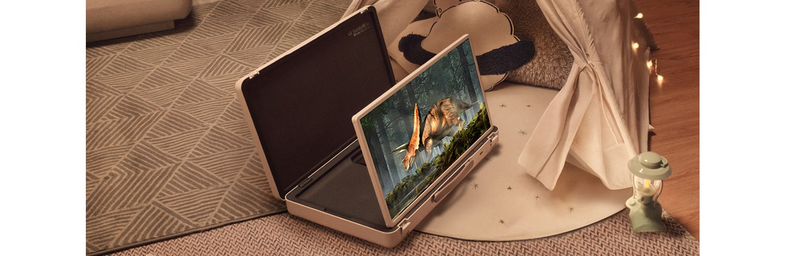 El estuche de la televisión LG StanbyME Go está abierto y la pantalla está desplegada. Dos niños en casa en un campamento improvisado con una tienda y luces cálidas y acogedoras. Están viendo un video en la pantalla de la StanbyME Go.