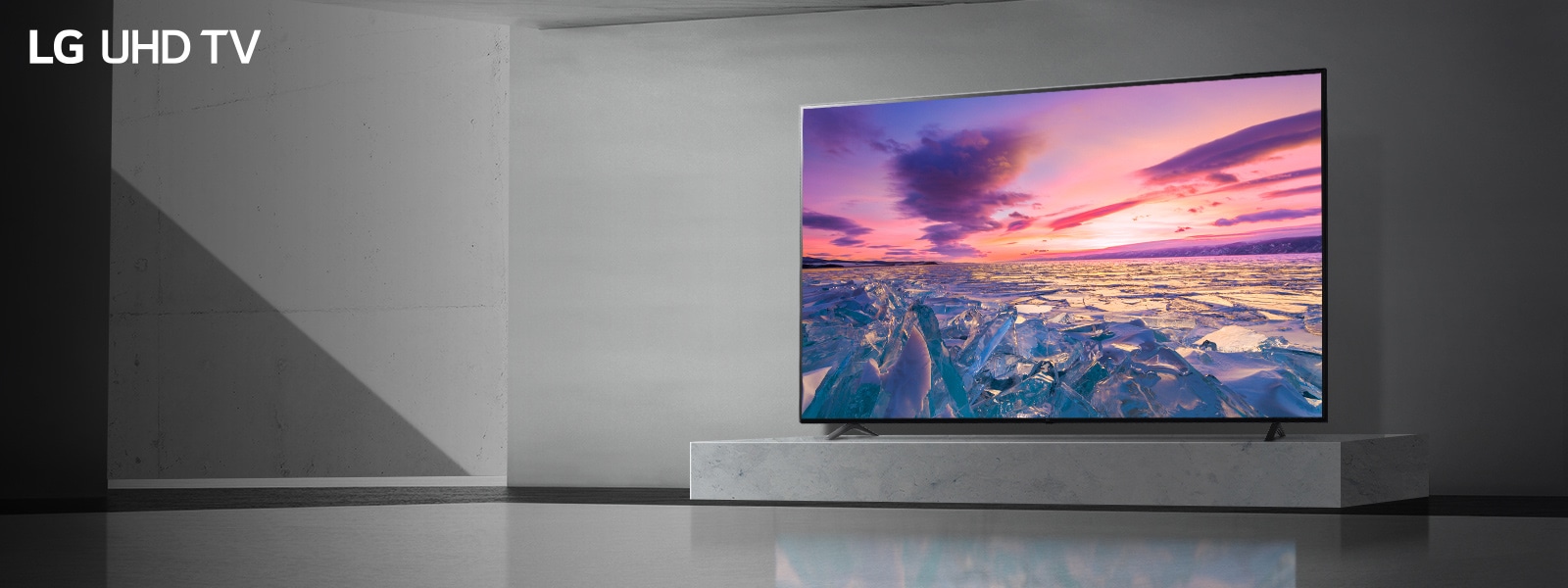 Imagen de un LG UHD AI THINQ TV colgado de una pared con la imagen de un amanecer entre glaciares
