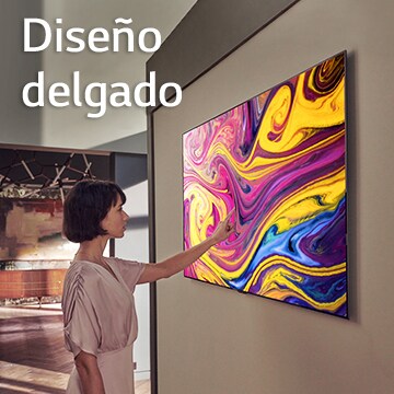 Una mujer está mirando un televisor colgado en la pared en el que se muestra una obra de arte.