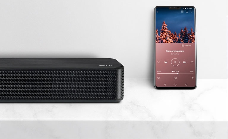 Plano detalle derecho de la Barra de Sonido LG con un Smartphone. Ambos dispositivos en una balda blanca. 