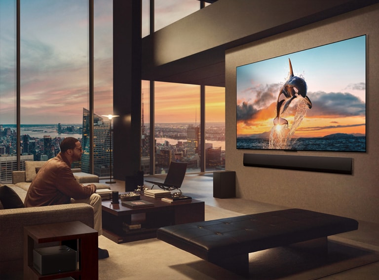 Avar elutuba vaatega linnapanoraamile. Seinal on LG OLED TV teler ja selle alla on paigaldatud LG Soundbar. Teleri One Wall disain võimaldab teleril olla seinaga tasa ja sulanduda hästi ruumi. Zero Connect Box on nähtav, kuid varjatud. 