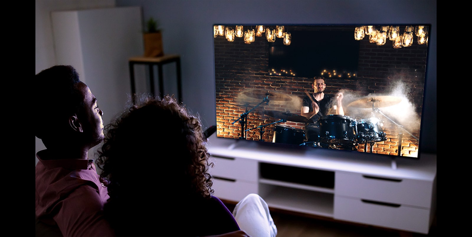 Couple sitting on a couch watching movie at its best quality  on TV (move the slide)