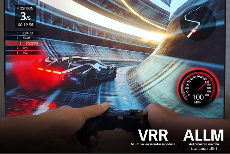 Kõrgresolutsioonis sujuvalt jooksvat kihutamismängu näitav ekraan koos selle ees mängupulti hoidva kahe käega