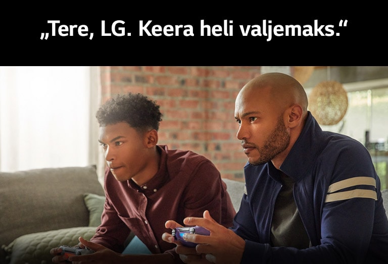 Kaks diivanil istuvat mängu süvenenud noorukit, kes hoiavad juhtmeta mängupulte